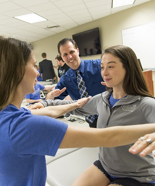 Student performing arm strength test with assistance from teacher.