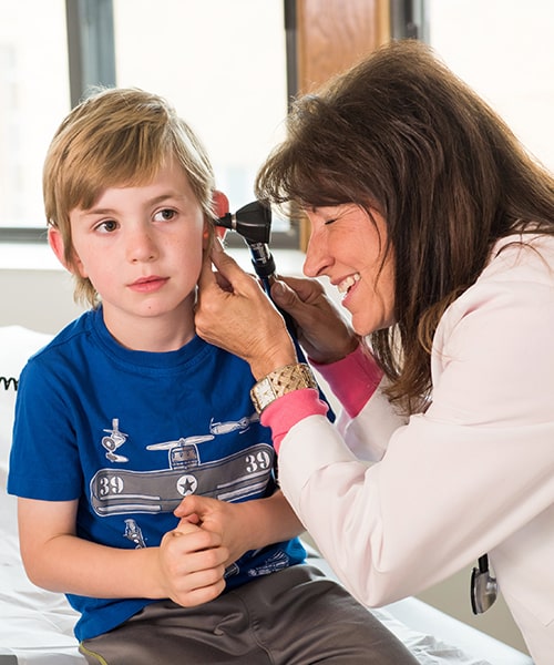 Female nurse practitioner giving a young boy a check up. 