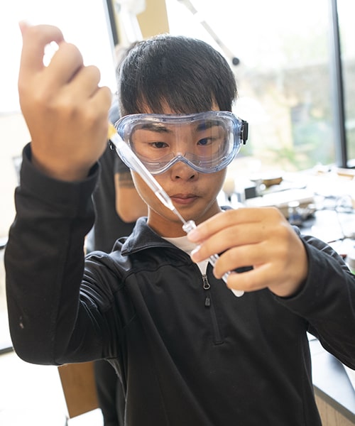 Student measuring out the right amount of chemical while performing an experiment in the lab. 