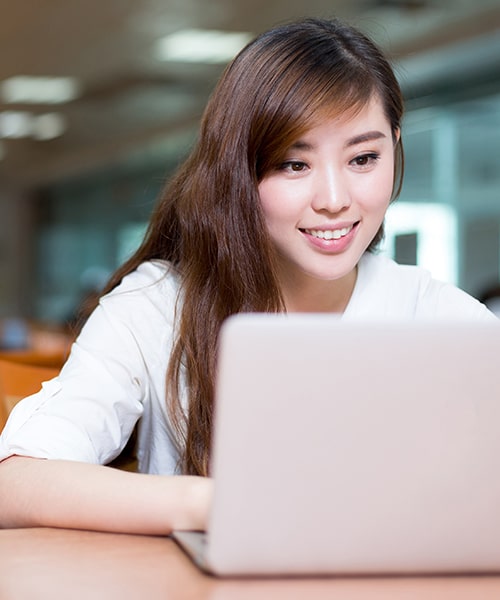 Female student working on laptop in the classroom. 