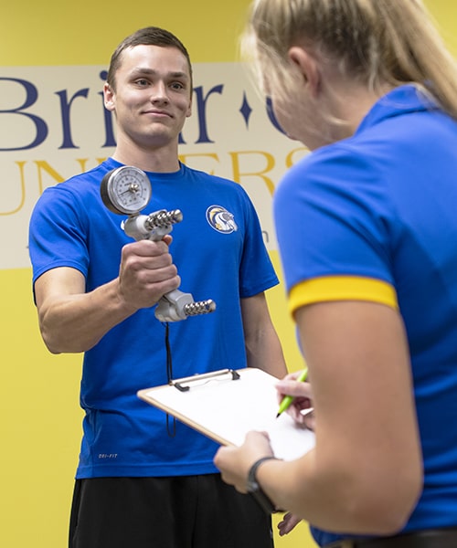 Male student performing grip strength test.