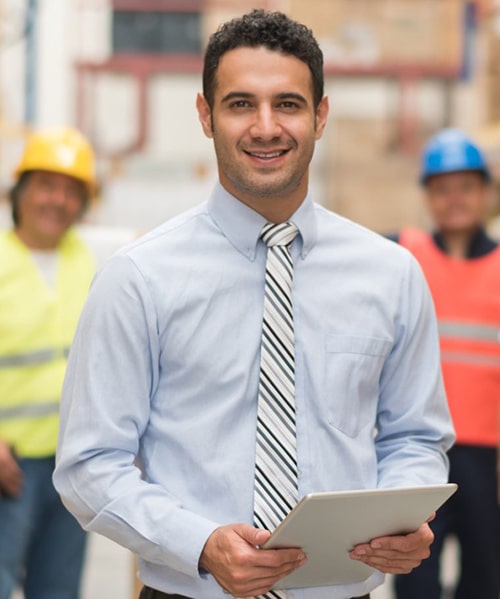 Male employee with clipboard in front of warehouse workers.