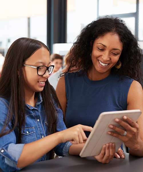 Male secondary education student teacher showing middle school students information on an ipad.