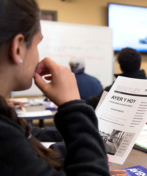 Female student following along as professor teaches spanish class.